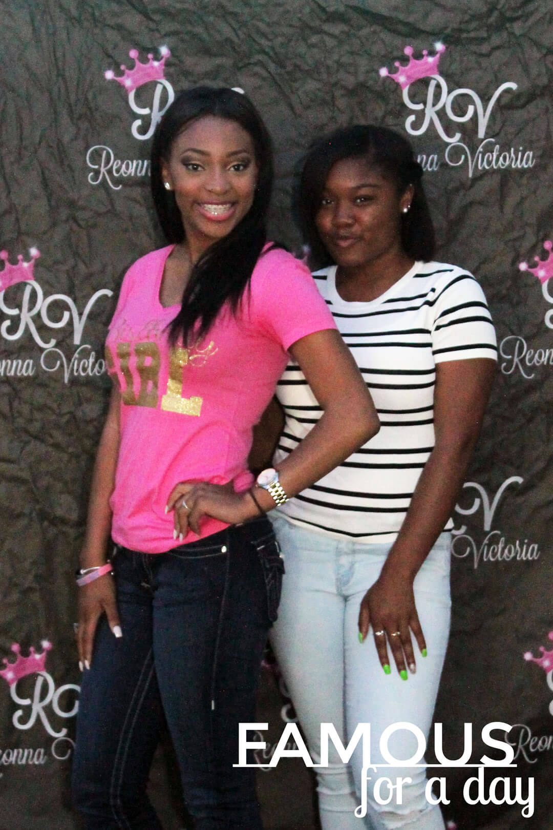 Two guests smiling and posing together at a red carpet event backdrop